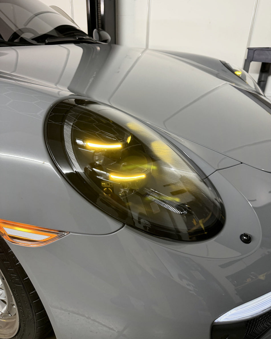 Close view of an installed 992.2-style V2 headlight showing yellow daytime running lights
