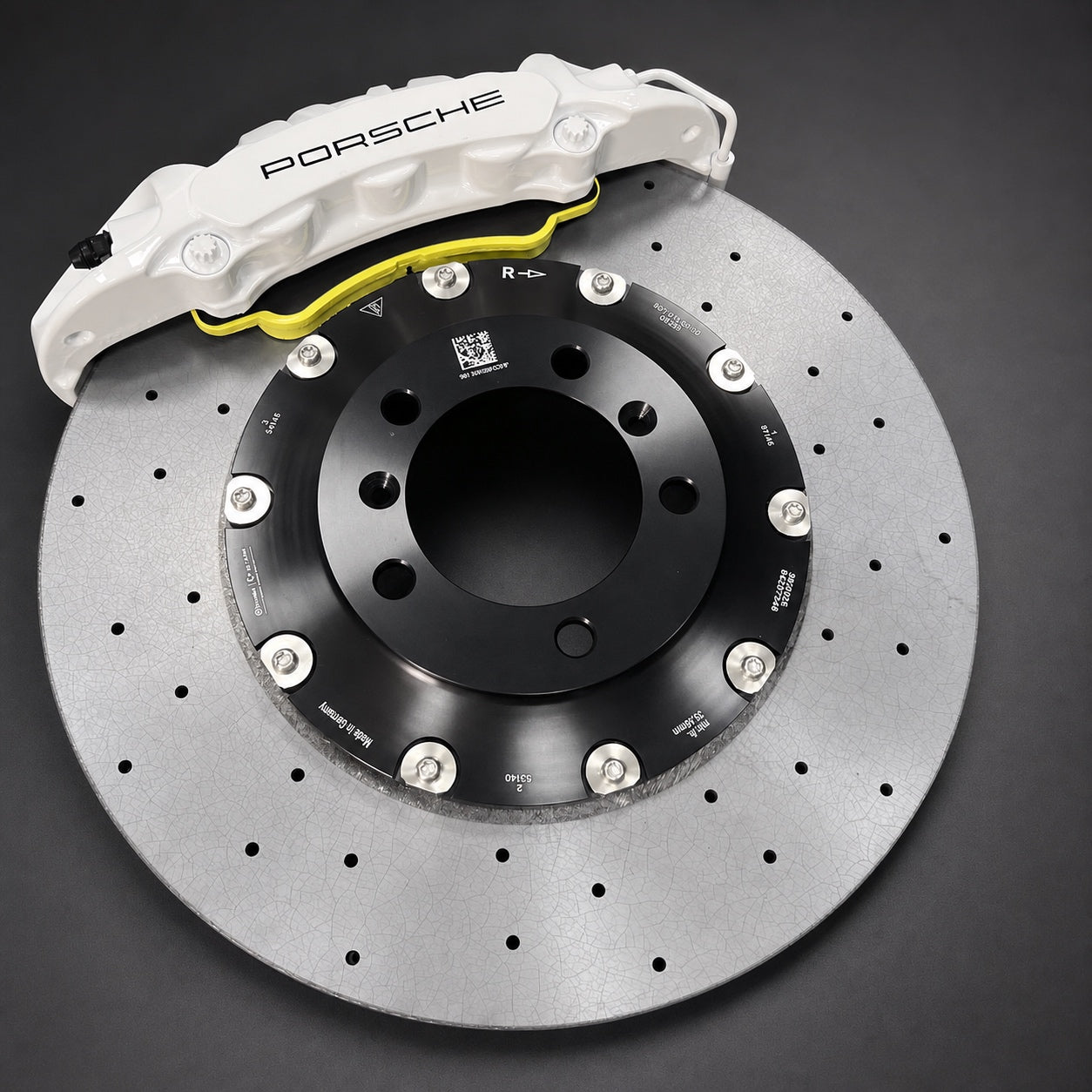 Front carbon ceramic rotor and white six-piston caliper shown on a graphite studio surface