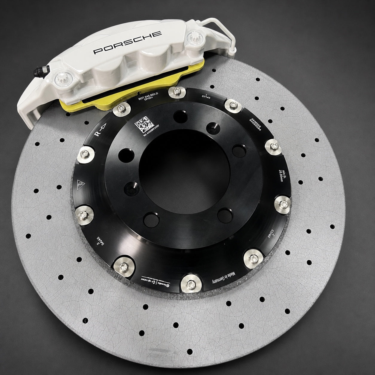 Rear carbon ceramic rotor and white four-piston caliper shown on a graphite studio surface