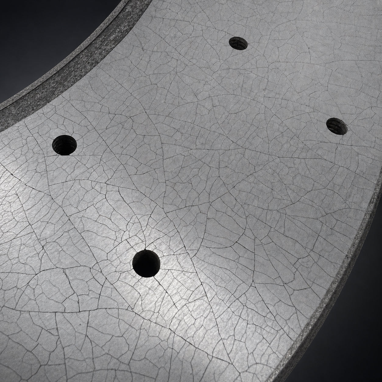 Macro detail of the drilled carbon ceramic rotor friction surface under controlled studio light