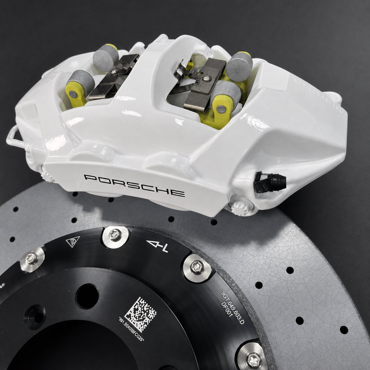 Close view of the white front caliper, pad-retention hardware and carbon ceramic rotor